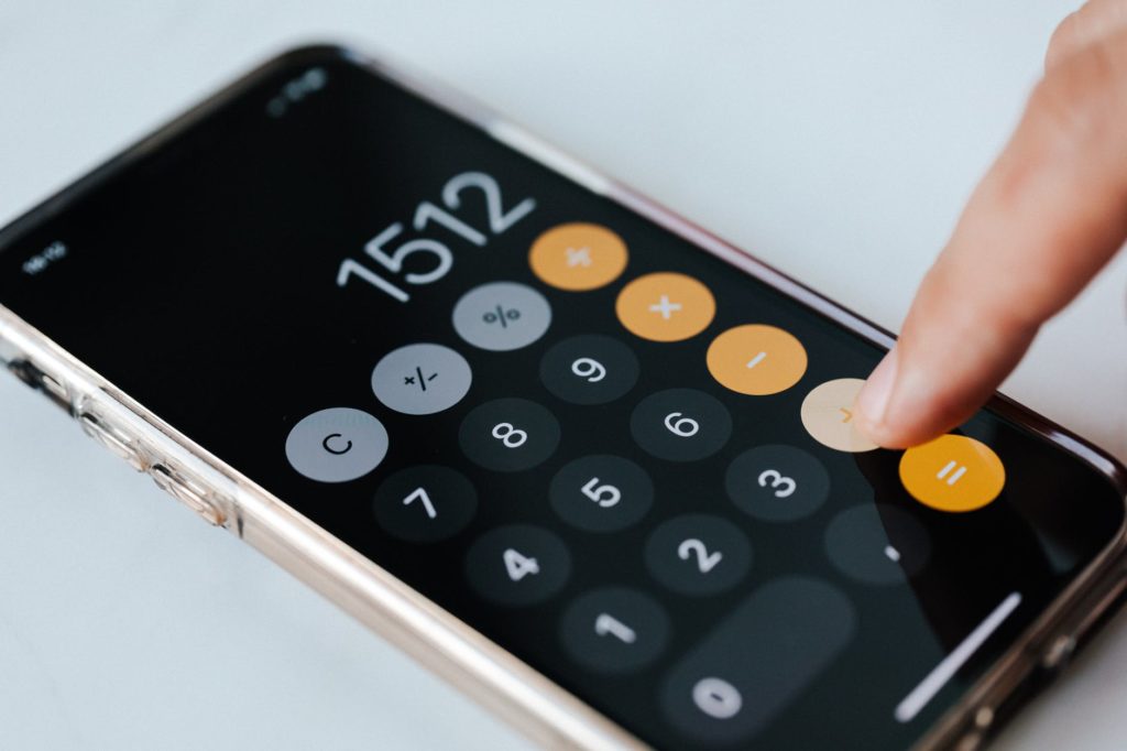 crop anonymous accountant using calculator app on smartphone